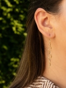 Modne złote kolczyki w kształcie spirali na kobiecym uchu