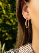 Modne złote kolczyki owalne w próbie 585 na uchu kobiety