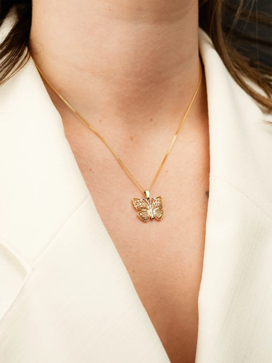 Piękna ażurowa zawieszka w kształcie motyla z wykończeniem w białym złocie na kobiecej szyi