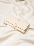 Złożone, duże beżowe etui na złotą biżuterię z widocznym logo marki Coomi ułożone na jasnym materiale