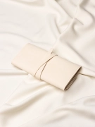 Tył złożonego etui podróżnego na biżuterię w kolorze beżowym na jasnym materiale