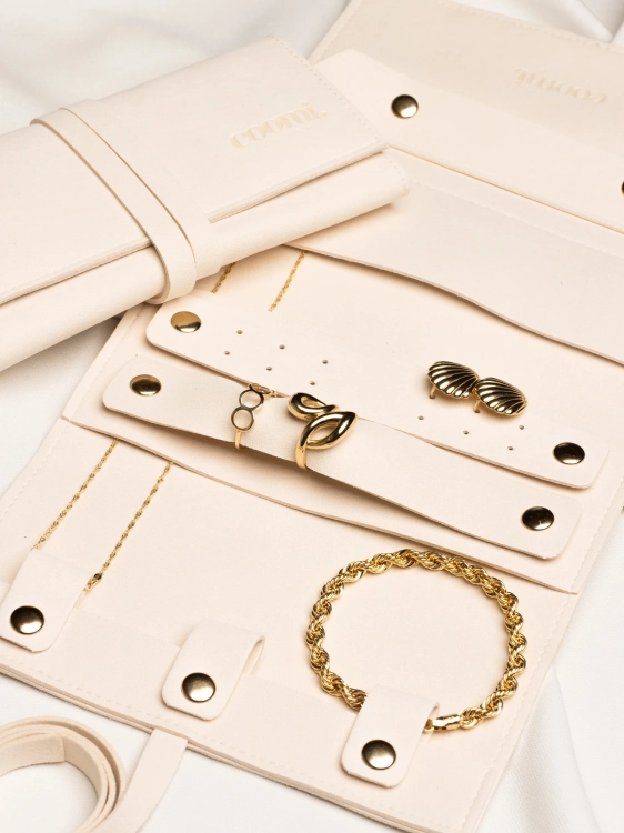 Rozłożone etui na złotą biżuterię, organizery z biżuterią oraz drugie zamknięte etui obok