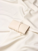 Złożone, beżowe etui na złotą biżuterię z widocznym logo marki Coomi ułożone na jasnym materiale