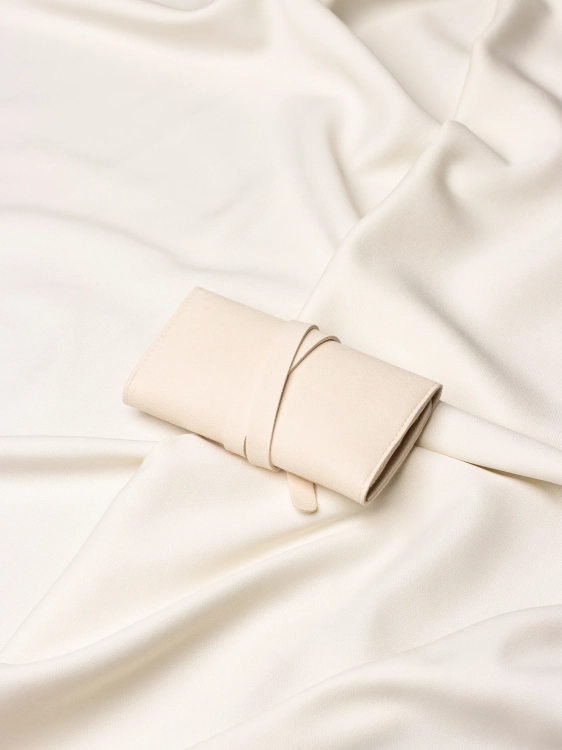 Złożone, beżowe etui na złotą biżuterię z widocznym logo marki Coomi ułożone na jasnym materiale