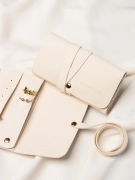 Zbliżenie na detale organizera na złotą biżuterię oraz zamknięte etui z logo Coomi w tle